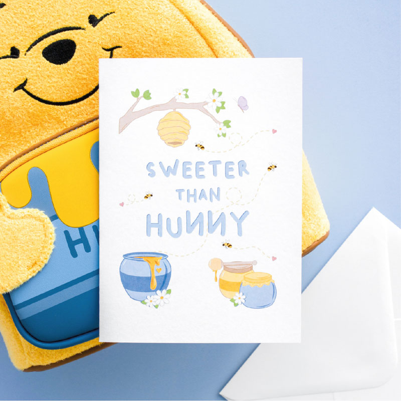 An anniversary or Valentine's day card with a hand drawn image of three pots of hunny, a tree branch with a hanging bee hive and a few bees flying around. Could easily be a scene from Winnie the Pooh. The card caption is: Sweeter Than Hunny